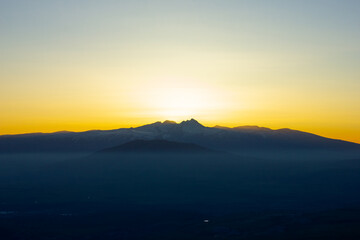 the sun goes down behind the mountain