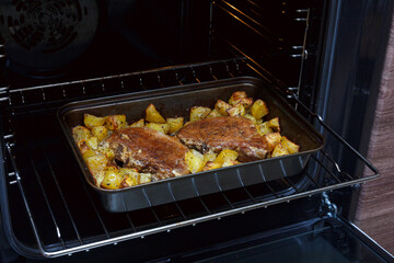 Two baked pork steaks with potatoes. Meat with potatoes in the oven. Homemade food. Pork meat stew with potatoes