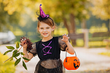 Portrait blonde girl in witch costume with pumpkin in her hands. Halloween kids.