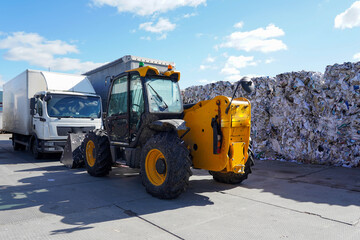 Photo of a yellow tractor against the background of garbage at a dump