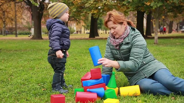 Mom and son play together with colored educational toy blocks collecting a pyramid.  Family games and outdoor activities in the parkchild, family, mother, boy, people, park, baby, fun, love, woman, ch