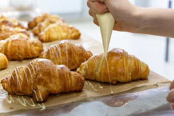 Baker decorating freshly baked croissant. Sweet handmade dessert