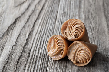 mini cone cake with whipped cream and toffee on wooden table