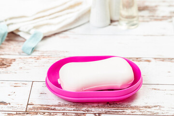 soap on pink plastic soap dish with towels on white wooden table in bathroom