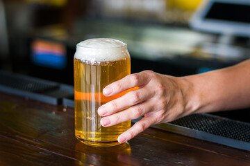 Bar server hand holding a cold tap beer.