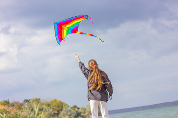 the girl launches a bright kite into the sky.