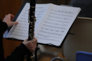 Child musician playing a musical instrument clarinet sitting in front of notes