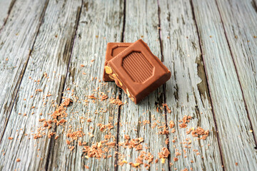 Pieces of chocolate with peanuts stacked face up on a wooden background