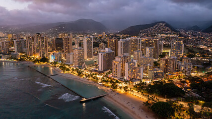 Aerial view of waikiki beach at night in Honolulu, Hawaii. Skyscrapers with lights can be seen with...