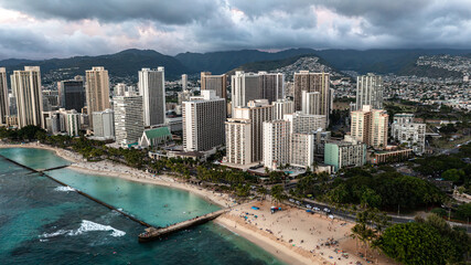 Naklejka premium Aerial view of waikiki beach in Honolulu, Hawaii. Skyscrapers can be seen with mountains and a sandy beach.