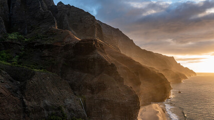 View of the Napali Coastline during sunset  at kalalau beach in Kauai, Hawaii. Peaks can be seen with several ridge lines and the ocean.