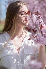girl smelling pink flowers on a blossoming tree © ms16_photo