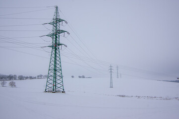 Landscape covered with snow and freeze, high voltage wires and poles on the meadow on Czech...