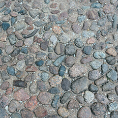 a fragment of a section of a country road made of stones of different sizes and shapes in the ancient Russian city of Pskov, Russia