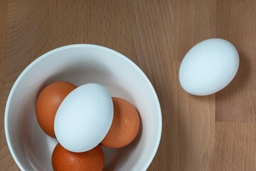 several fresh chicken eggs in a ceramic cup on a wooden background. Healthy eating concept