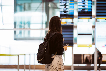 Tourist woman at the airport waiting for her flight. Wearing a mask for covid 19 protection. Lifestyle. Travel