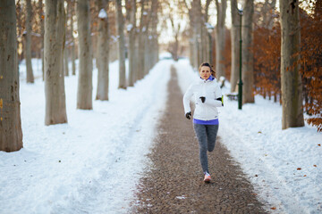Fototapeta premium Full length portrait of young woman in white jacket jogging
