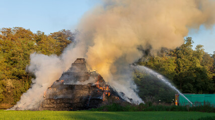 Die Feuerwehr versucht brennende Heuballen zu löschen