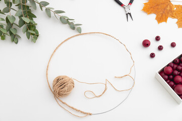 Workpiece of a wreath made of wire, twine, red beads and leaves. Flat lay.