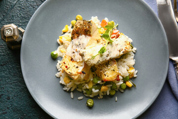 Plate with tasty baked cod fillet, rice and vegetables on dark background