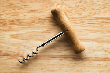Corkscrew with a wooden handle on a wooden surface.