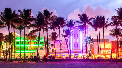 Miami Beach Ocean Drive hotels and restaurants at sunset. City skyline with palm trees at night....