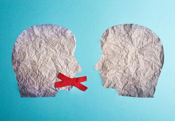 Two silhouette faces look at each other, one has a red cross over his mouth, censorship free speech