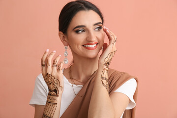 Beautiful Indian woman with henna tattoo on color background