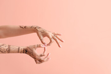 Female hands with henna tattoo on color background