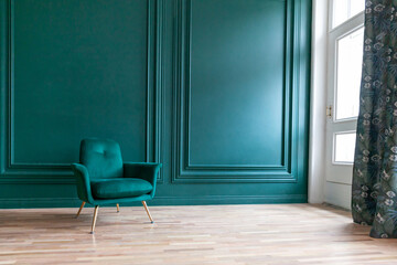 Beautiful luxury classic blue green clean interior room in classic style with green soft armchair. Vintage antique blue-green chair standing beside emerald wall. Minimalist home design.