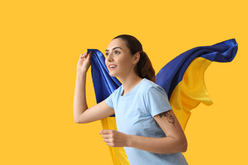 Young woman with Ukrainian flag on color background