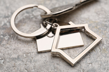 Key with house shape keychain on grunge background, closeup