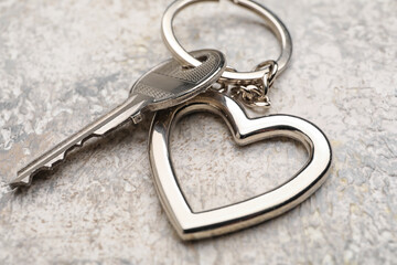 Key with heart shape keychain on grunge background, closeup