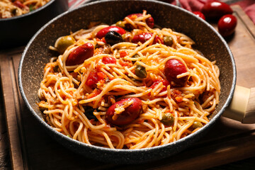 Frying pan of tasty Pasta Puttanesca on table