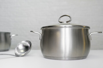 Stainless steel pot, stockpot and a ladle on white table, eco friendly kitchen utensils without harm, harmless safe for people