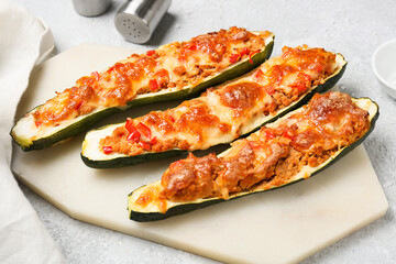 Board with meat stuffed zucchini boats on light background
