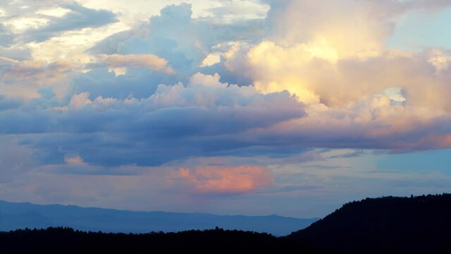 Magical blue and orange clouds swirl over the mountain at sunset. Timelapse, relaxation weather dramatic beauty atmosphere background