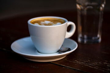 White cup of espresso coffee on wooden table. Space to copy your text.