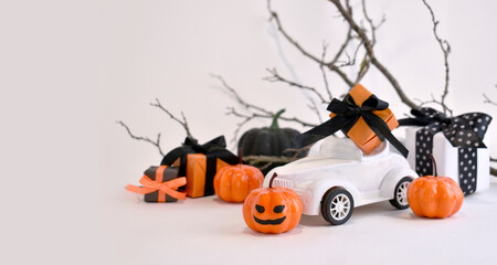 Fototapeta premium Halloween decorations. Close up retro toy car with pumpkins, gifts over tree branches. Creepy and funny concept. Halloween trick treat greeting layout background for holidays sale. Banner.
