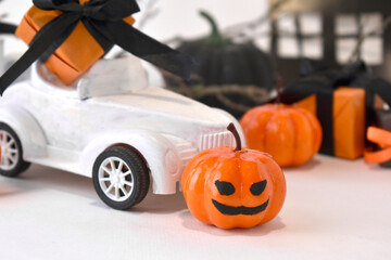 Halloween decorations. Close up retro toy car with pumpkins, gifts over tree branches. Creepy and funny concept. Halloween trick treat greeting layout background. Jack lantern toy