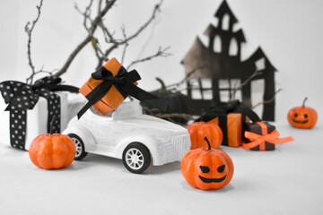 Halloween decorations. Close up retro toy car with pumpkins, gifts over tree branches. Horror and funny concept. Halloween trick treat greeting layout background for holidays sale.