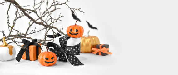 Mock up Halloween background with gifts, pumpkins and scary tree branches on white. Halloween trick treat concept for greeting card or sale banner. Spooky decorations with copyspace.