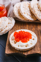 Crispy rice crackers with red caviar on dark wooden background, closeup