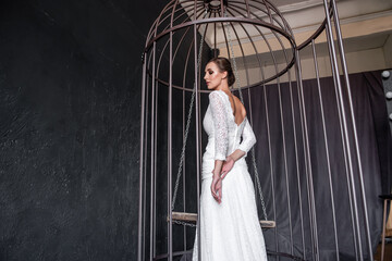 Fashion bride in an iron cage, unhappily looking out from behind bars. Life out of will.