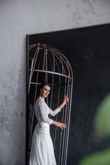 Obraz premium Reflection in the mirror of bride in cage on gray concrete background. Patriarchal marriage concept