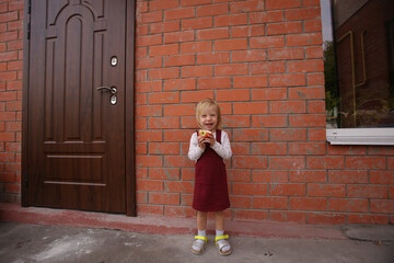 a girl in a red sundress, yellow sandals laughs, holding an apple in her hand
