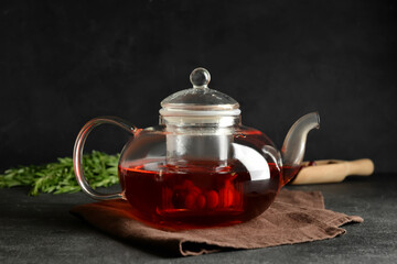 Teapot with delicious cranberry tea on dark background