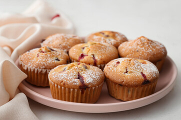 Plate with delicious cranberry muffins on table