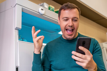 Excited millennial scientist showing emotions of joy about victory in online lottery in room with laboratory box in UV light. Amazed worker of scientific laboratory win money celebration success