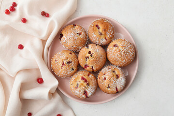 Plate with delicious cranberry muffins on white background